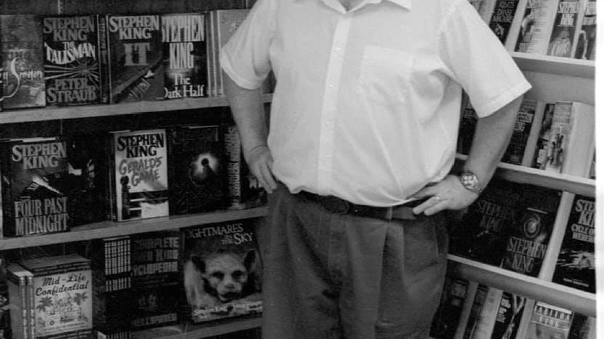 a man standing in front of a book shelf