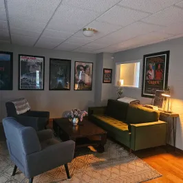 Cozy living room with sofas, coffee table, movie posters, and a lamp.